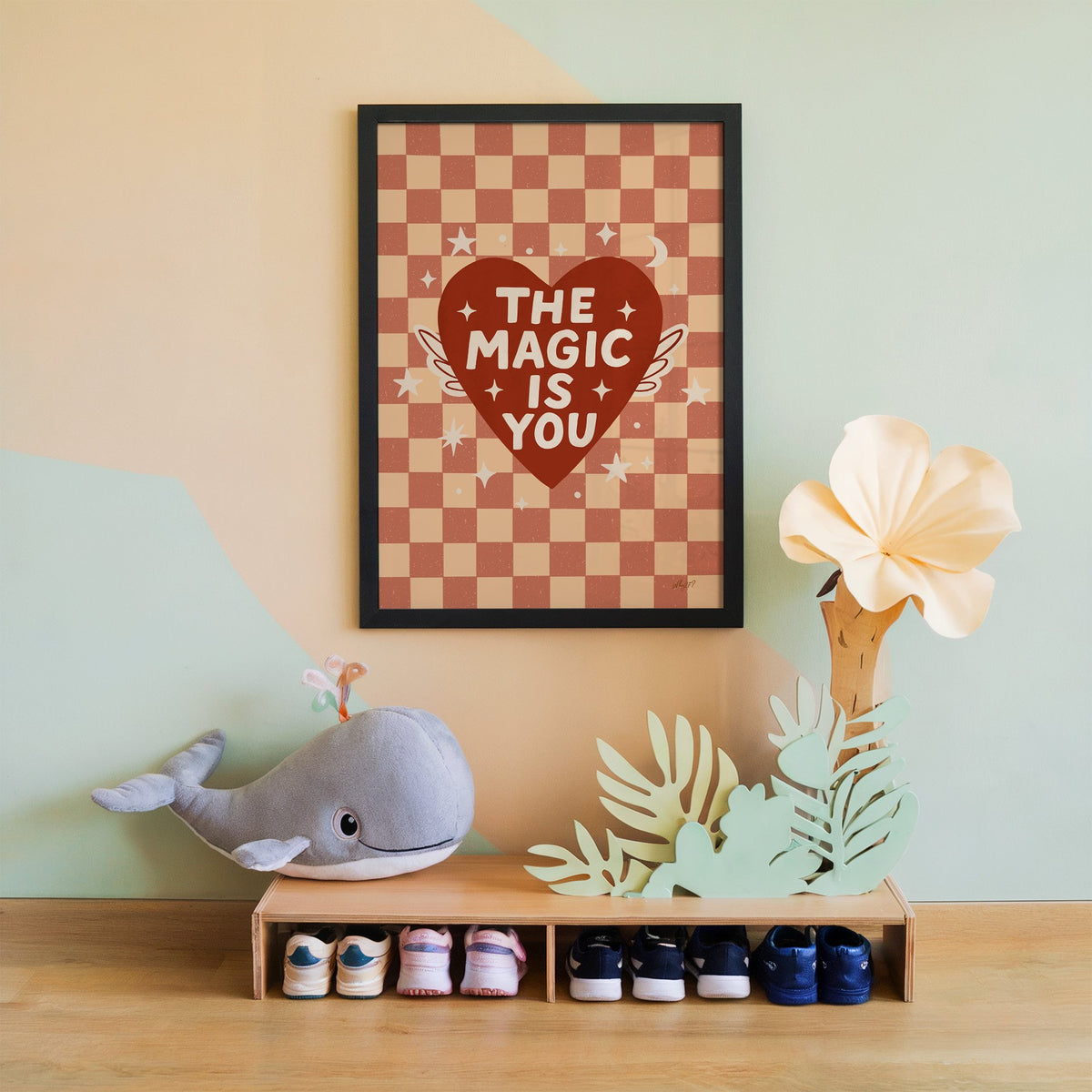 The magic is you winged heart nursery print in a black frame on a mint and peach wall above a whale plush