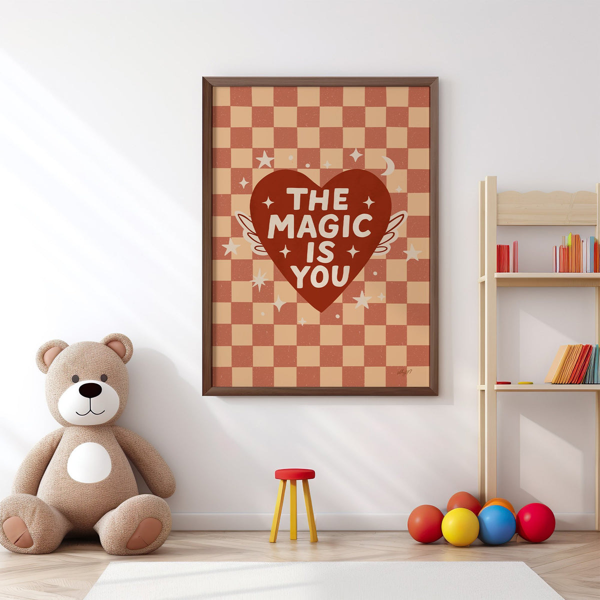 The magic is you winged heart nursery print in a walnut frame above a big teddy bear by a bookshelf