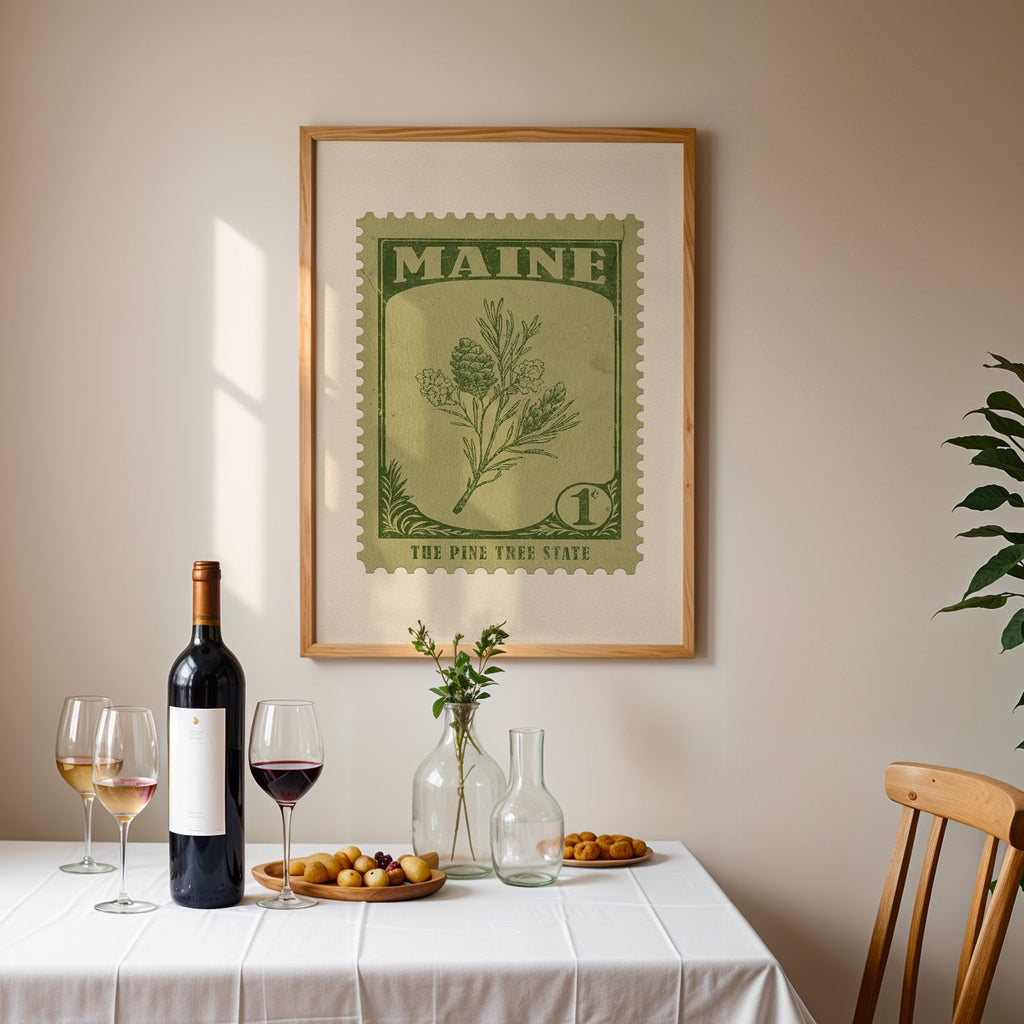 Maine stamp print framed on the wall above a dining table set with wine, glasses and olives