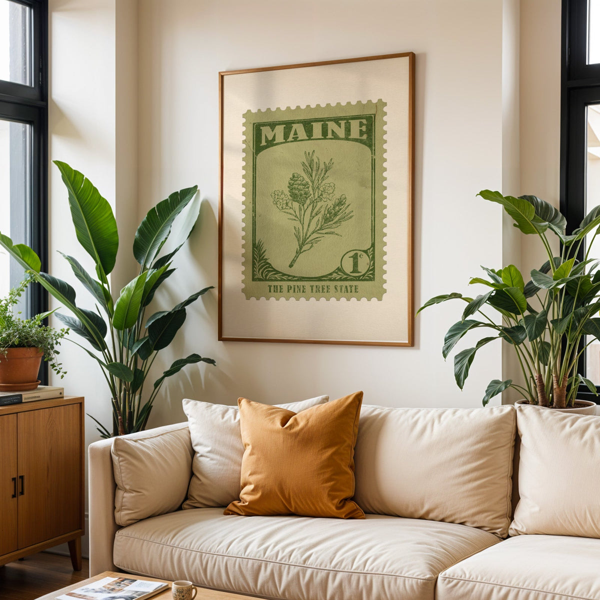 Maine state flower print framed above a cream sofa with an ochre cushion and large plants either side