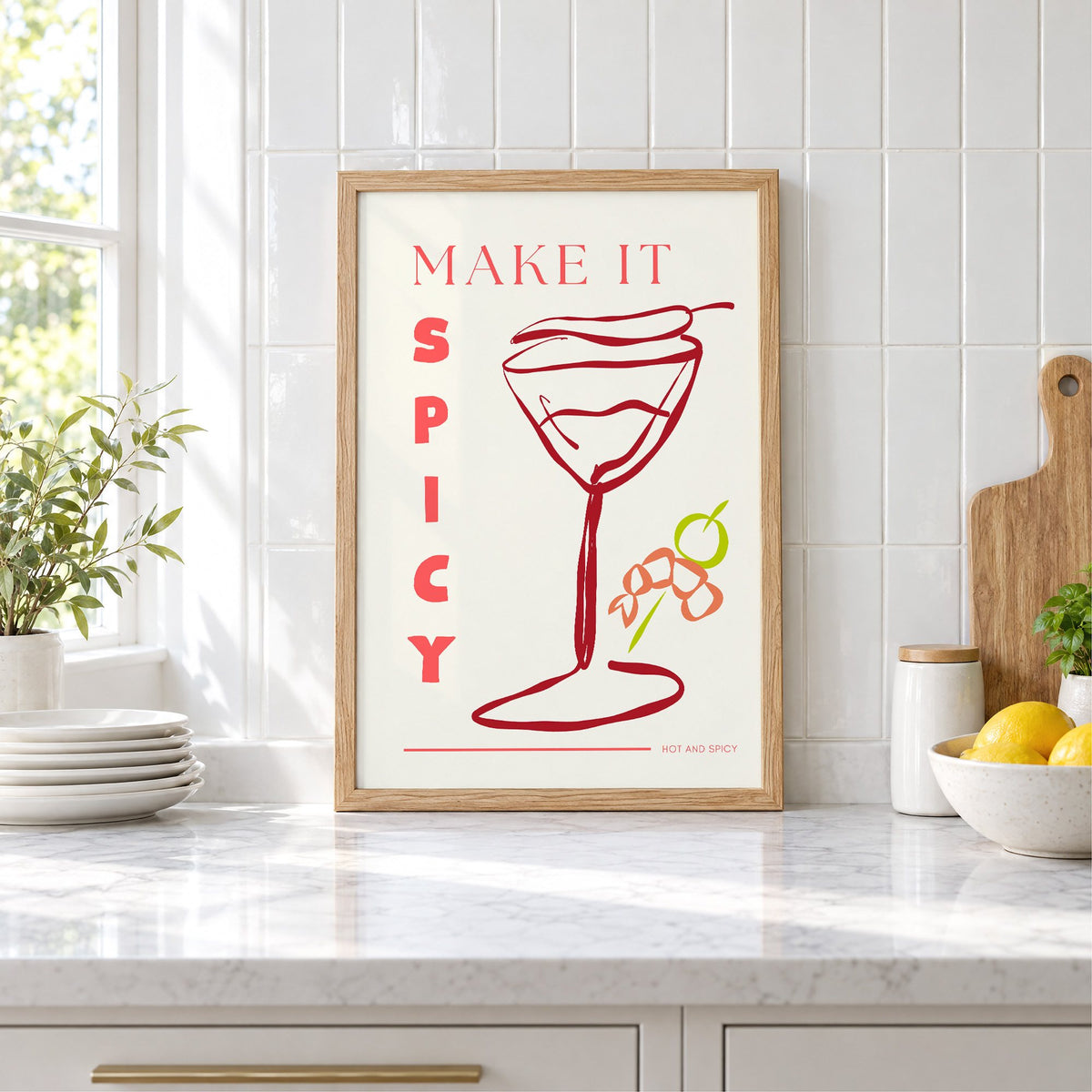 Make It Spicy martini line art print in an oak frame leaning on a marble counter by white tiles and lemons