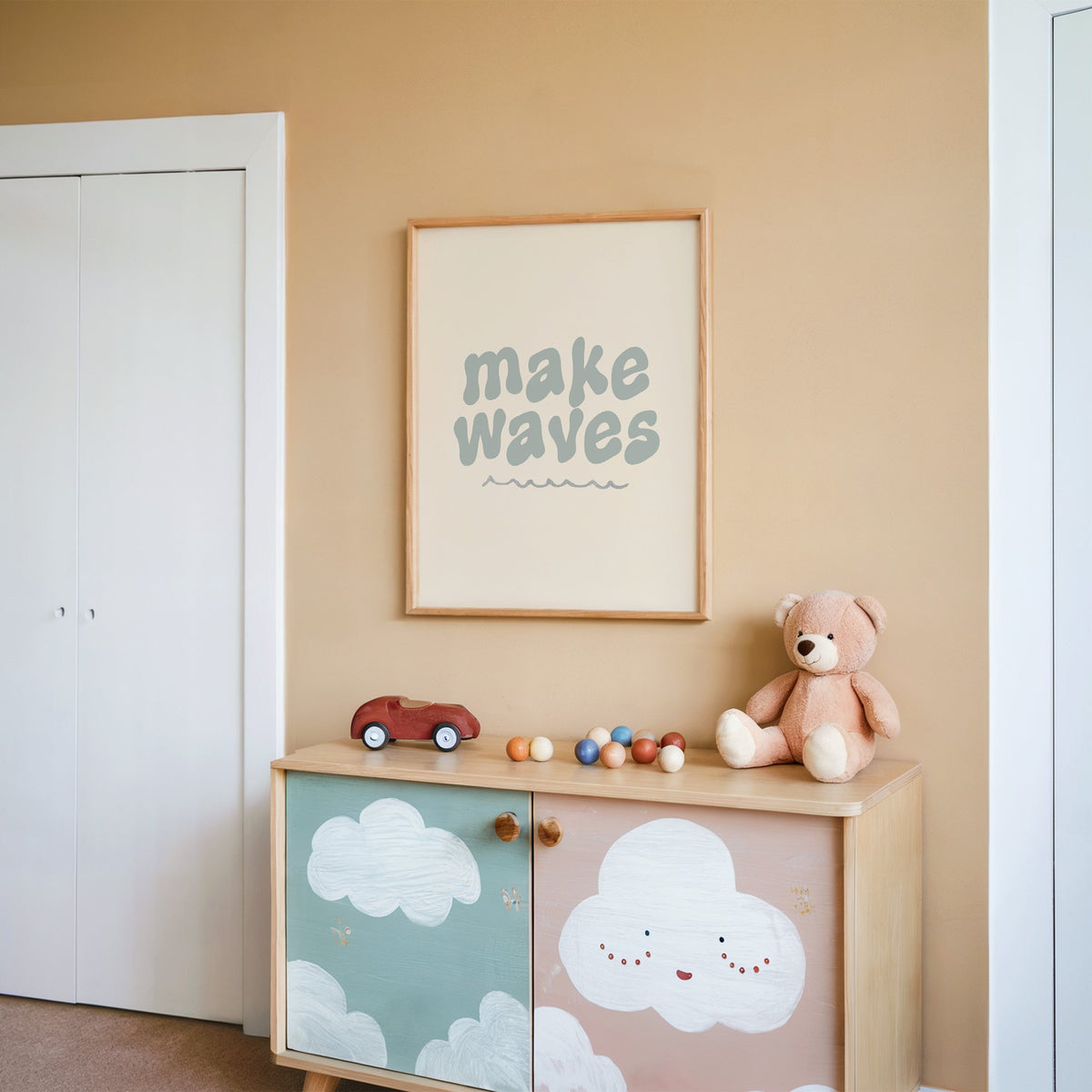Make waves typography nursery print in an oak frame on a peach wall above a cloud-painted cabinet