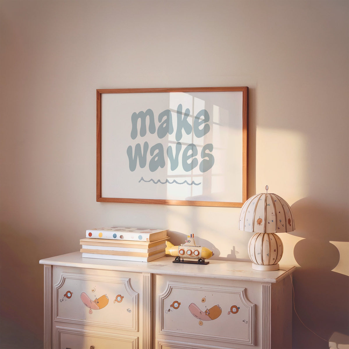 Landscape make waves typography nursery print in a cherry wood frame above a painted dresser and lamp