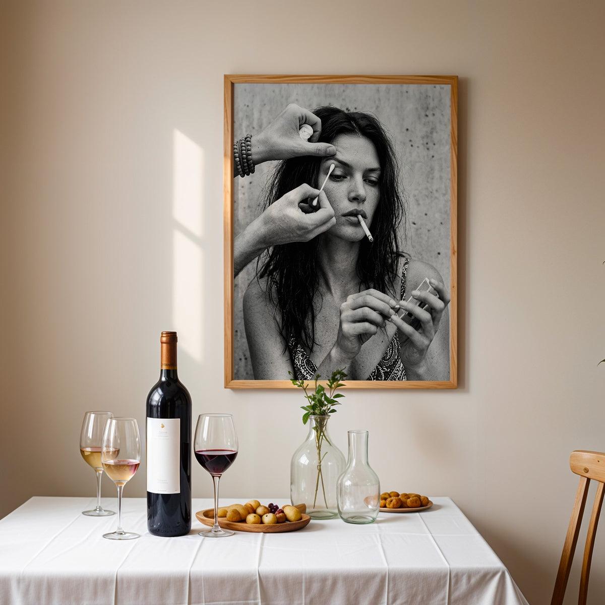 Makeup artist hands with cotton swab at eye print in an oak frame above a table set with red wine and glasses