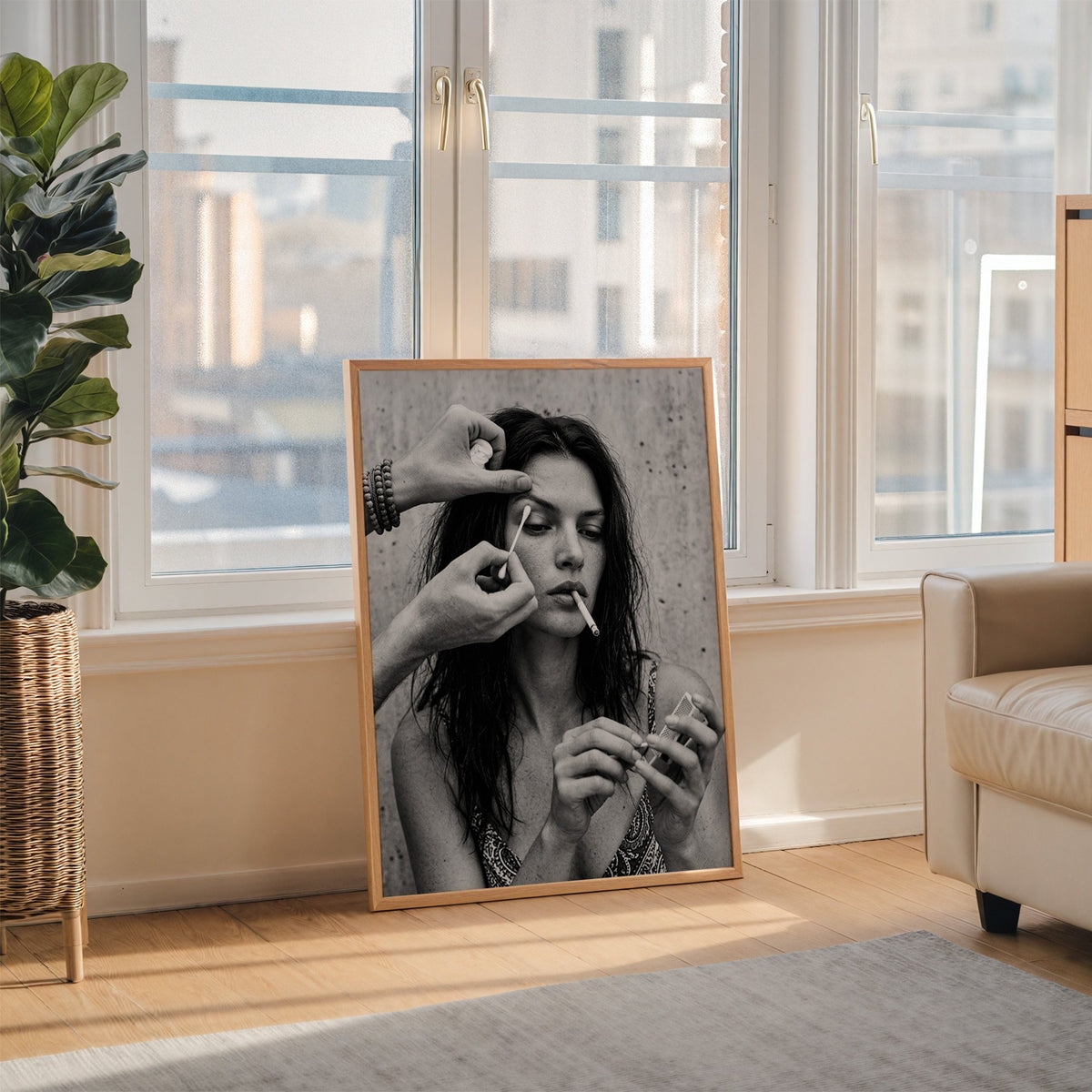 Makeup artist hands with cotton swab at eye print in an oak frame leaning on the floor beside a fiddle leaf fig