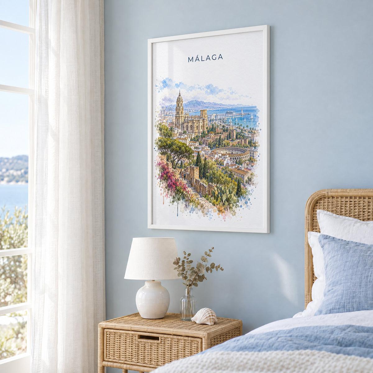 Málaga watercolor print in a white frame on a pale blue wall beside a rattan bed in a coastal bedroom