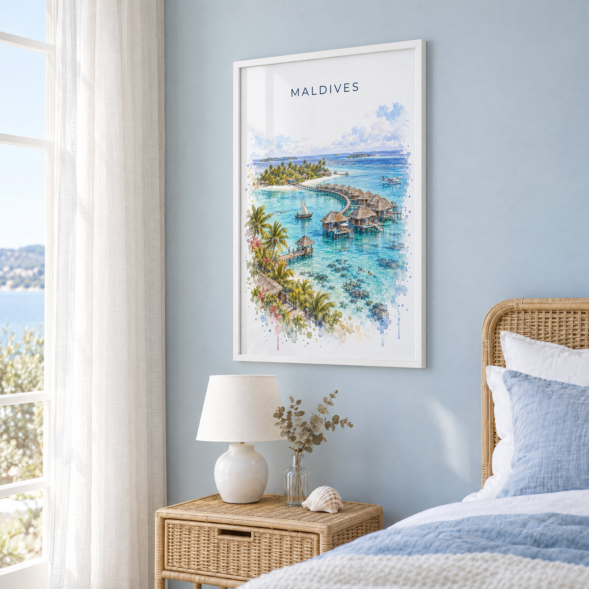 Maldives watercolor print in a white frame on a pale blue wall beside a rattan bed in a coastal bedroom
