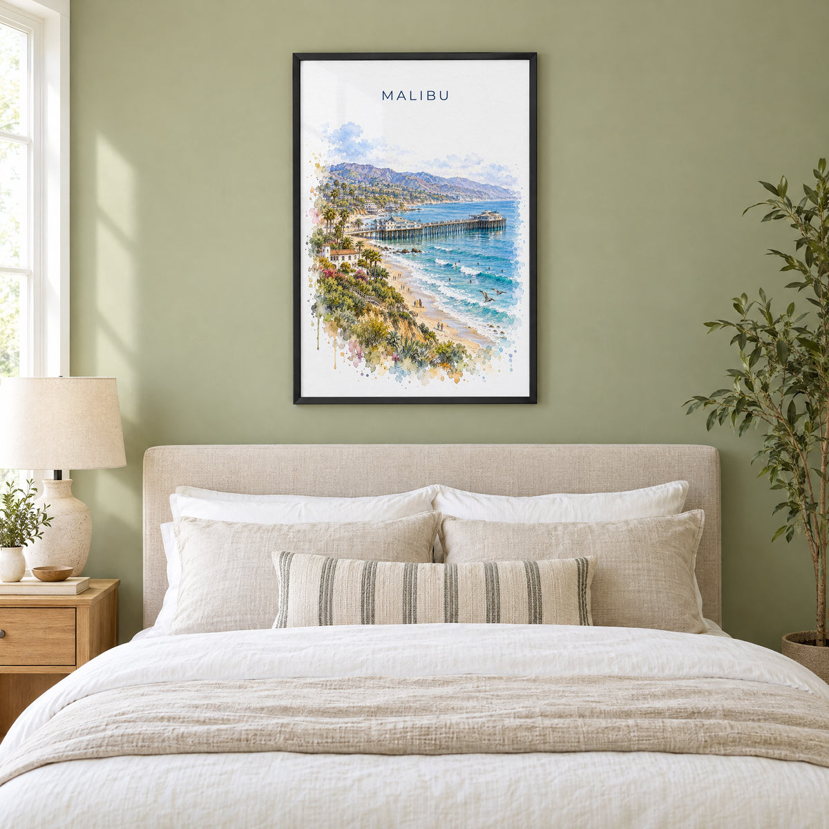 Malibu watercolor print in a black frame above an upholstered headboard in a sage green bedroom
