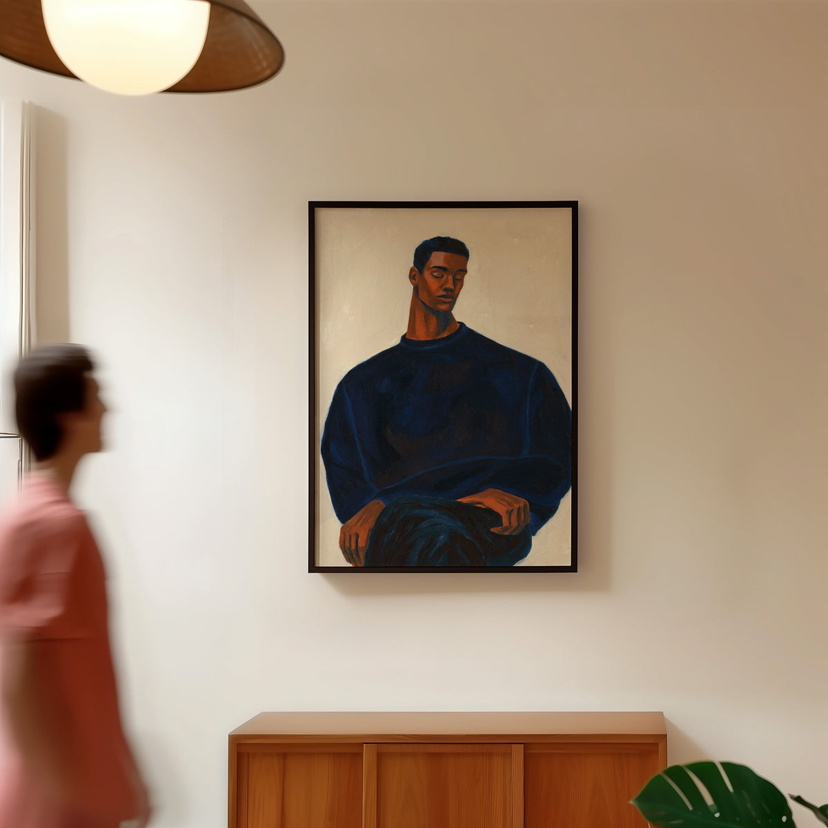 Seated man portrait print in a black frame in a hallway under a rattan pendant