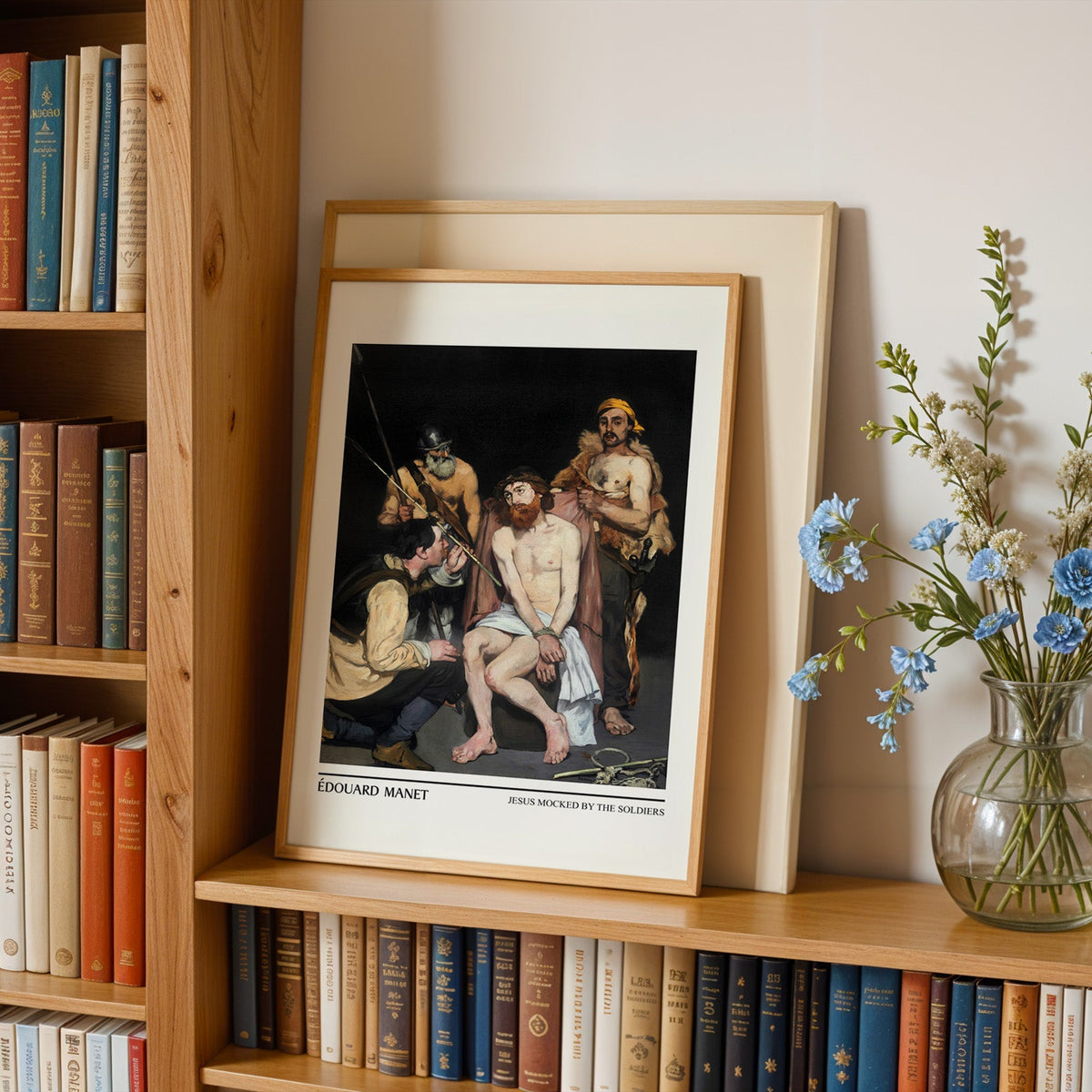 French salon painting print in an oak frame leaning on a bookshelf beside flowers