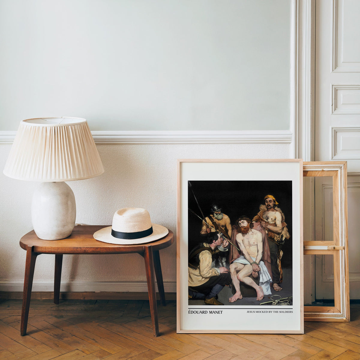 Christian art poster in a light wood frame leaning by a bench and hat