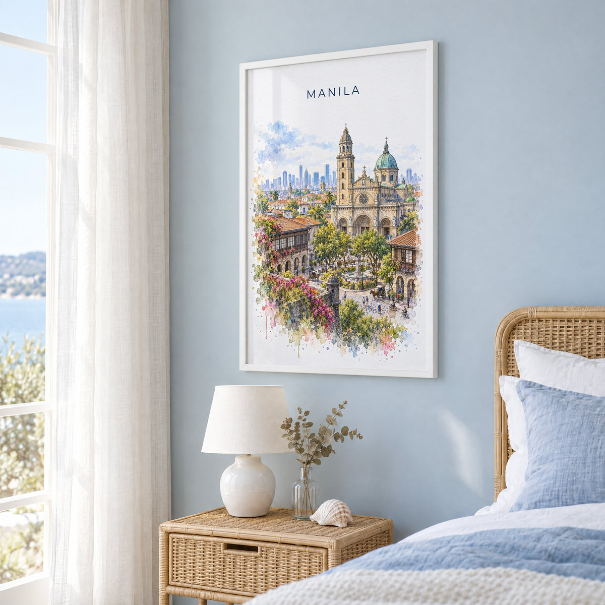 Manila watercolor print in a white frame on a pale blue wall beside a rattan bed in a coastal bedroom