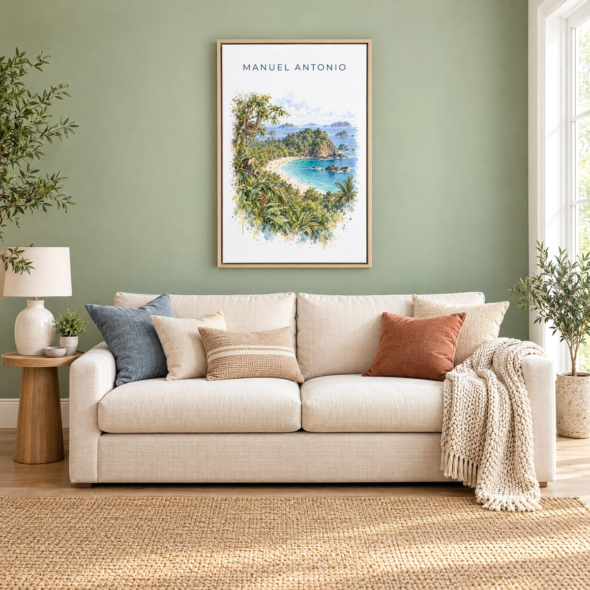 Manuel Antonio watercolor print as a natural floater canvas above a cream linen sofa on a sage green wall