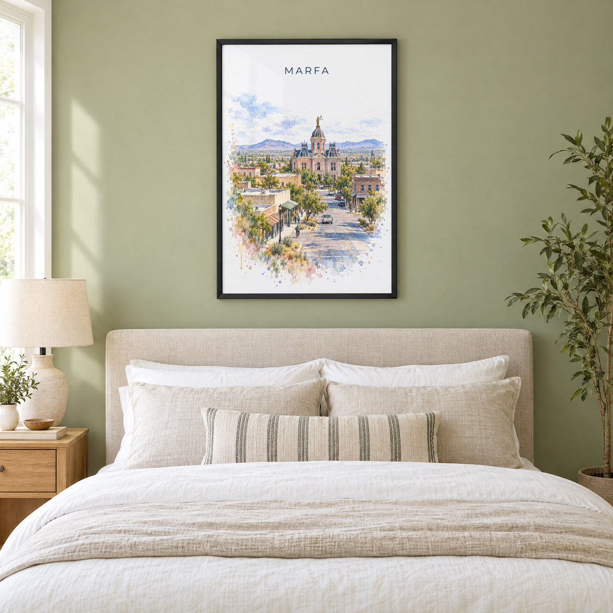 Marfa watercolor print in a black frame above an upholstered headboard in a sage green bedroom
