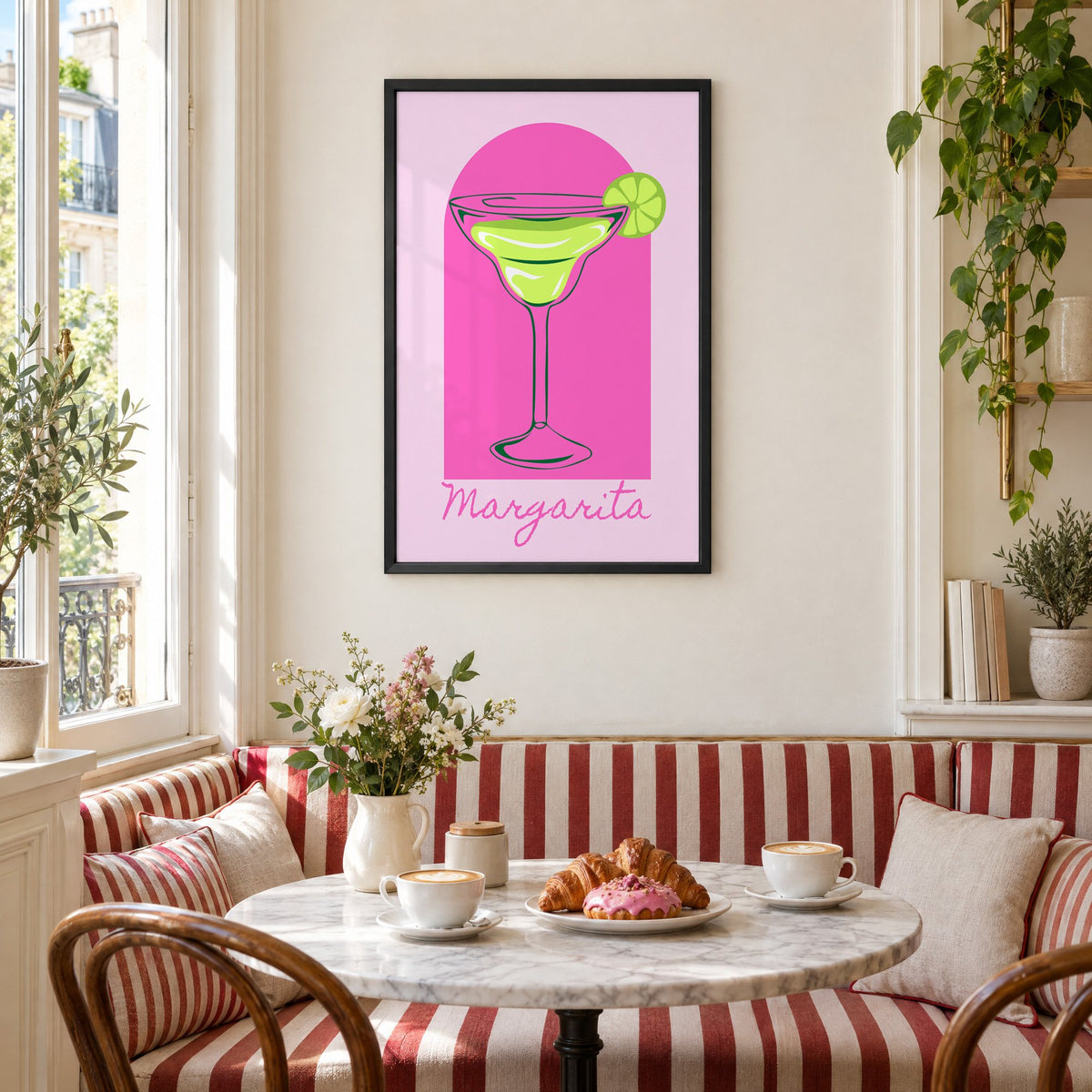Margarita glass and lime pink arch print in a black frame above a striped cafe breakfast nook with cappuccino and pastries
