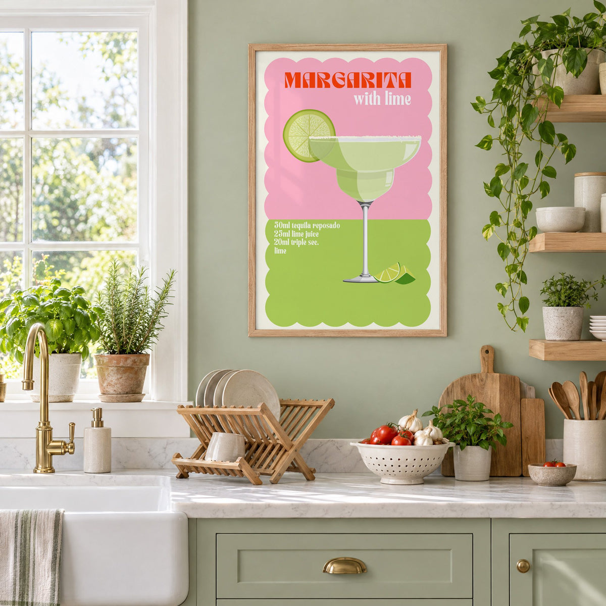 Margarita with lime scalloped print in an oak frame on a sage green kitchen wall beside a farmhouse sink and herbs