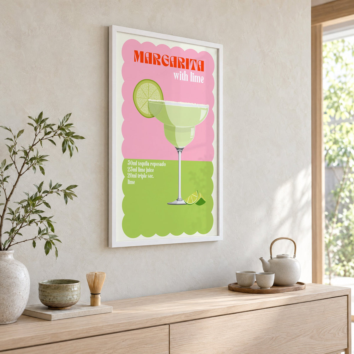 Margarita with lime scalloped print in a white frame above a pale wood console with a matcha tea set