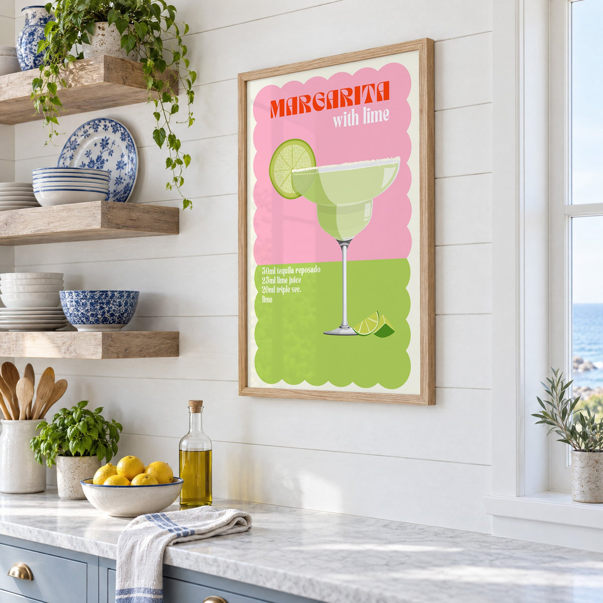 Margarita with lime scalloped print in an oak frame in a white coastal kitchen beside blue and white plates
