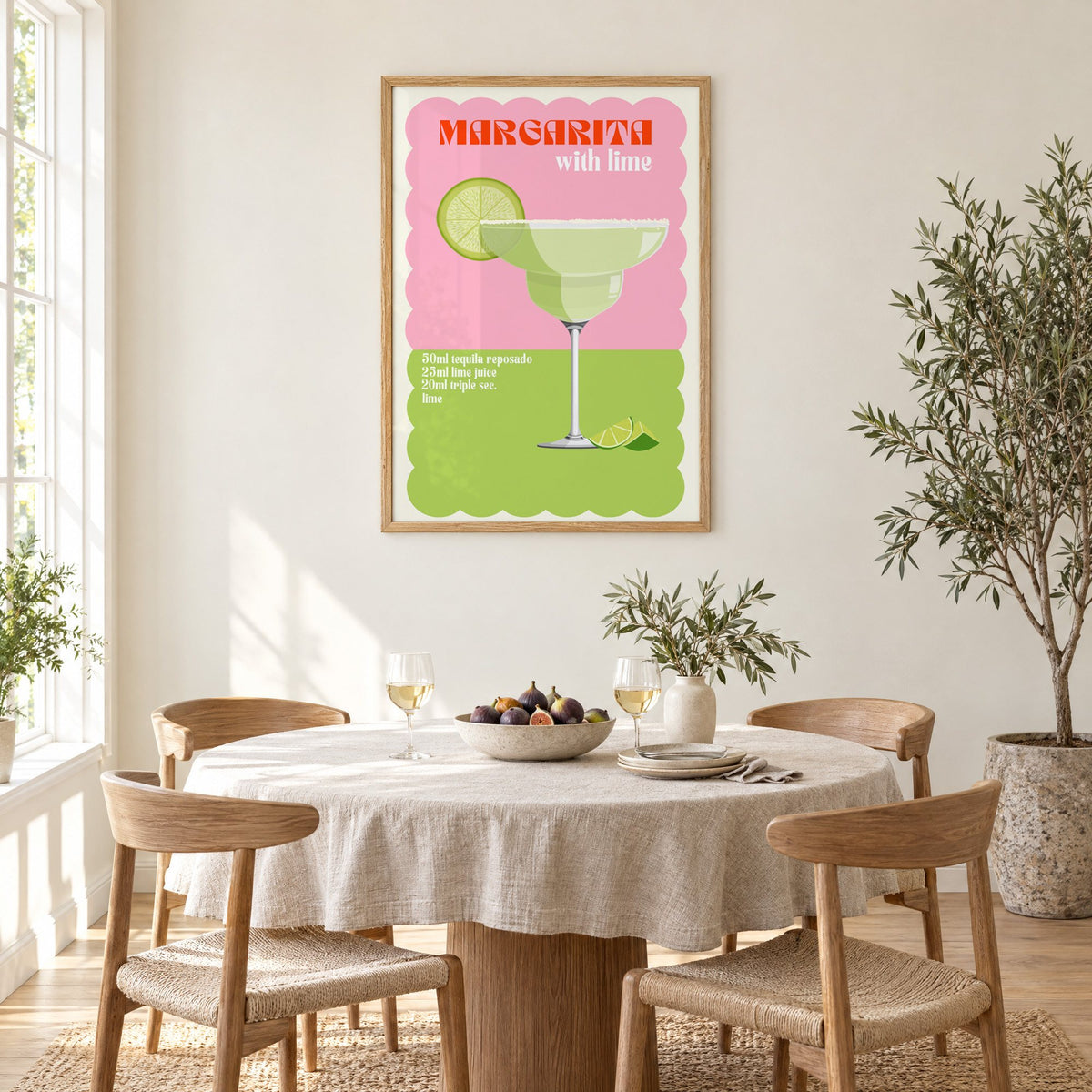Margarita with lime scalloped print in an oak frame above a round linen-covered dining table with figs and wine
