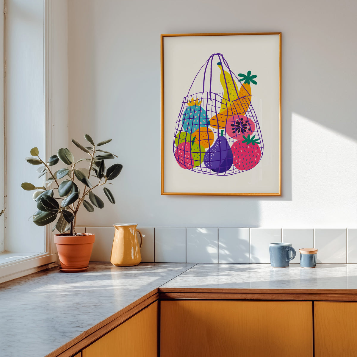 Fruit market bag print in a gold frame above a marble counter with a yellow jug