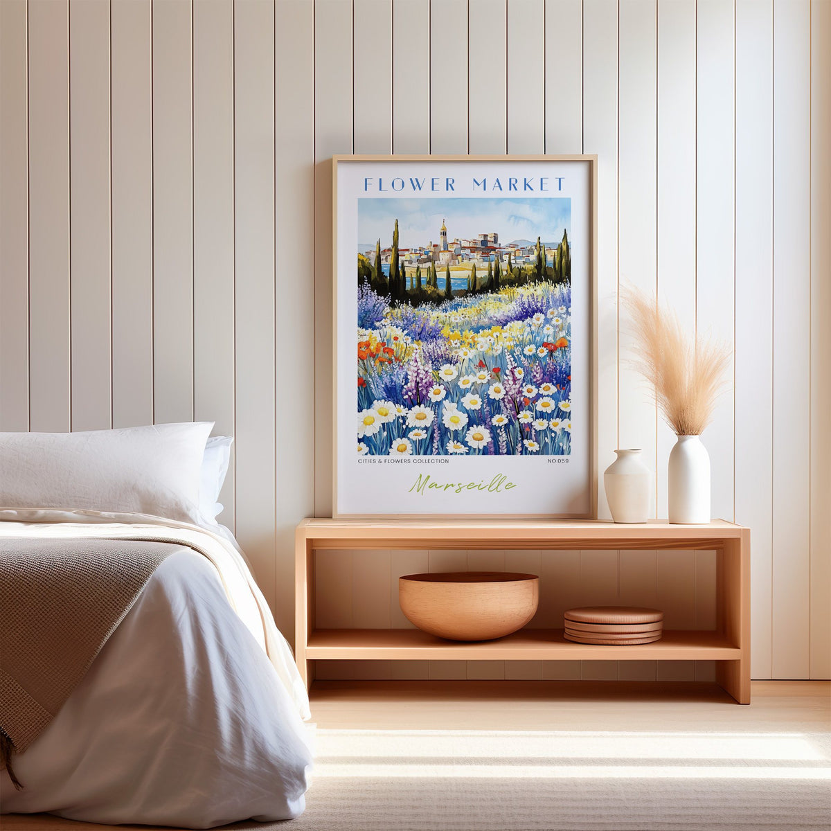 Marseille flower market print in an oak frame on a wood bench against a white shiplap bedroom wall with pampas grass