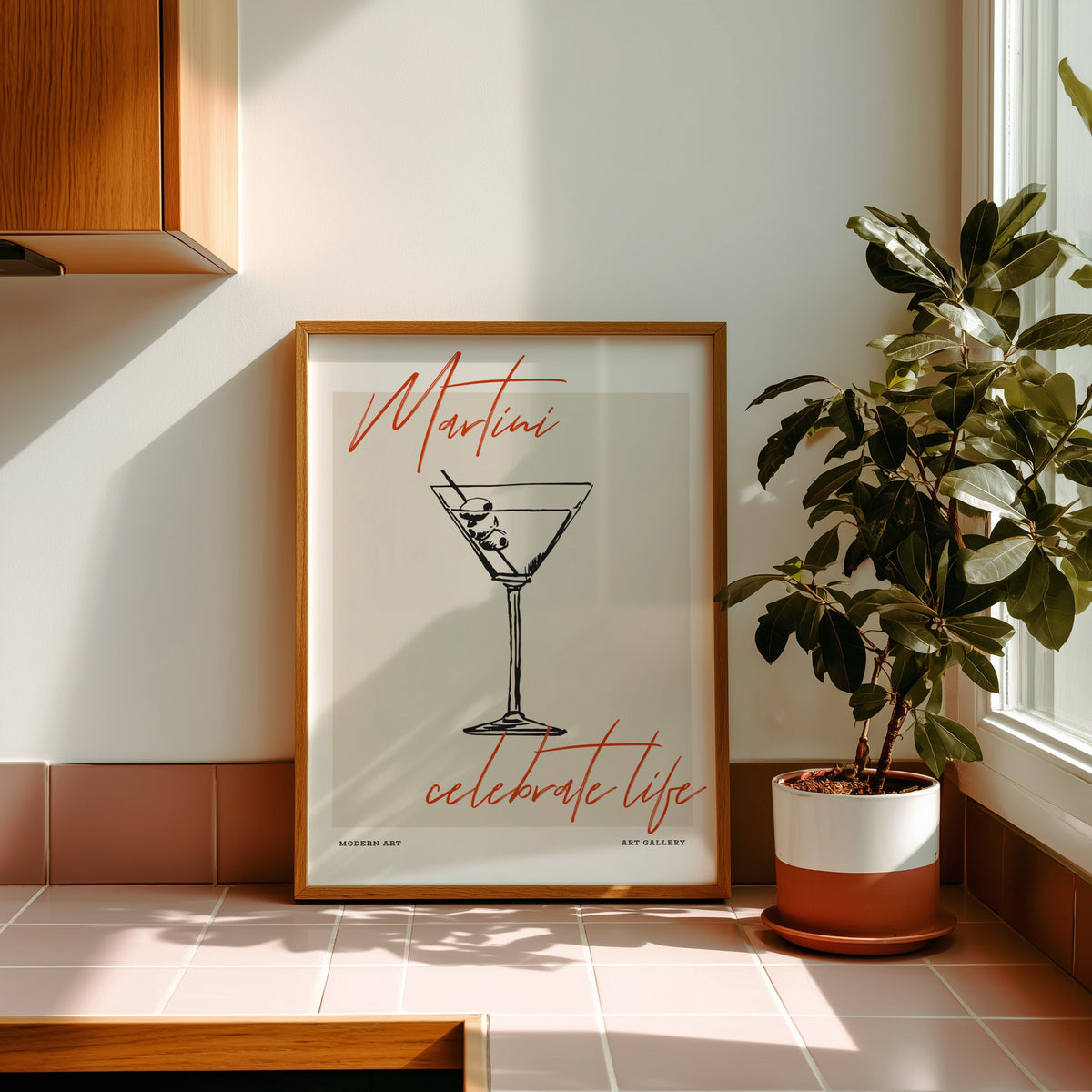Martini Celebrate Life print in an oak frame on pink tiles in afternoon sun