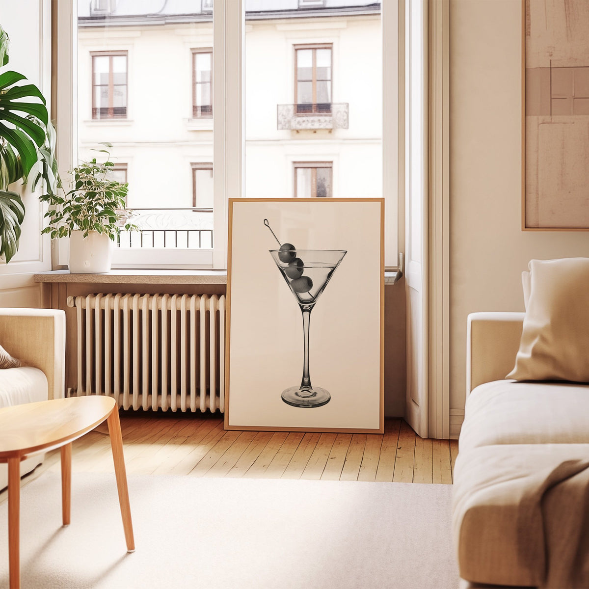 Martini glass with three olives on white print in an oak frame leaning by a French window in a living room
