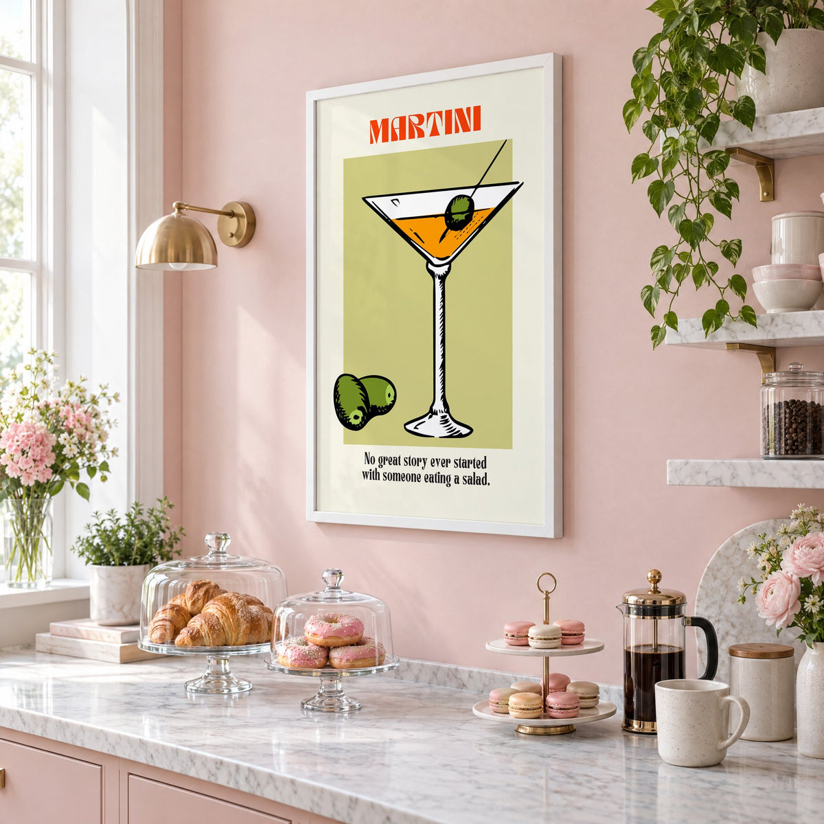 MARTINI sage block olives cocktail print in a white frame on a blush pink wall above a patisserie counter with croissants and macarons, seen at an angle