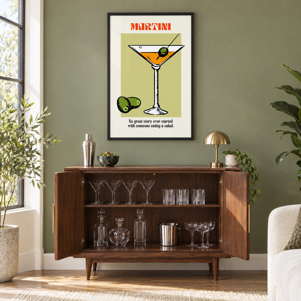 MARTINI sage block olives cocktail print in a black frame on an olive green wall above a walnut bar cabinet with glassware