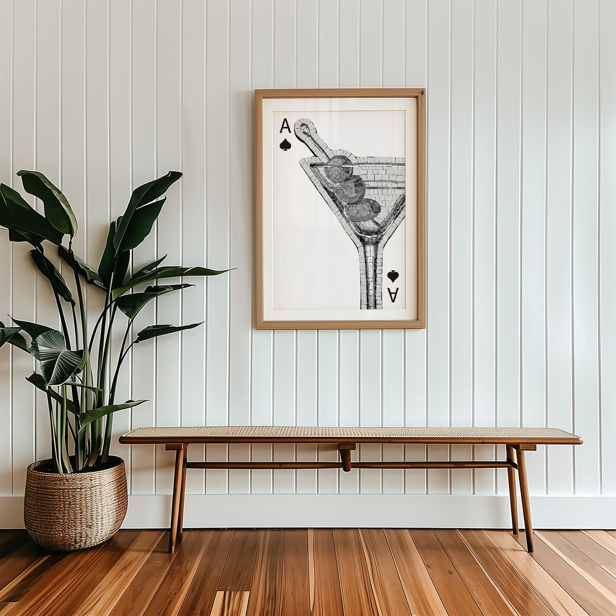 Mosaic martini glass on an ace of spades card print in a wood frame with a white mat above a cane bench