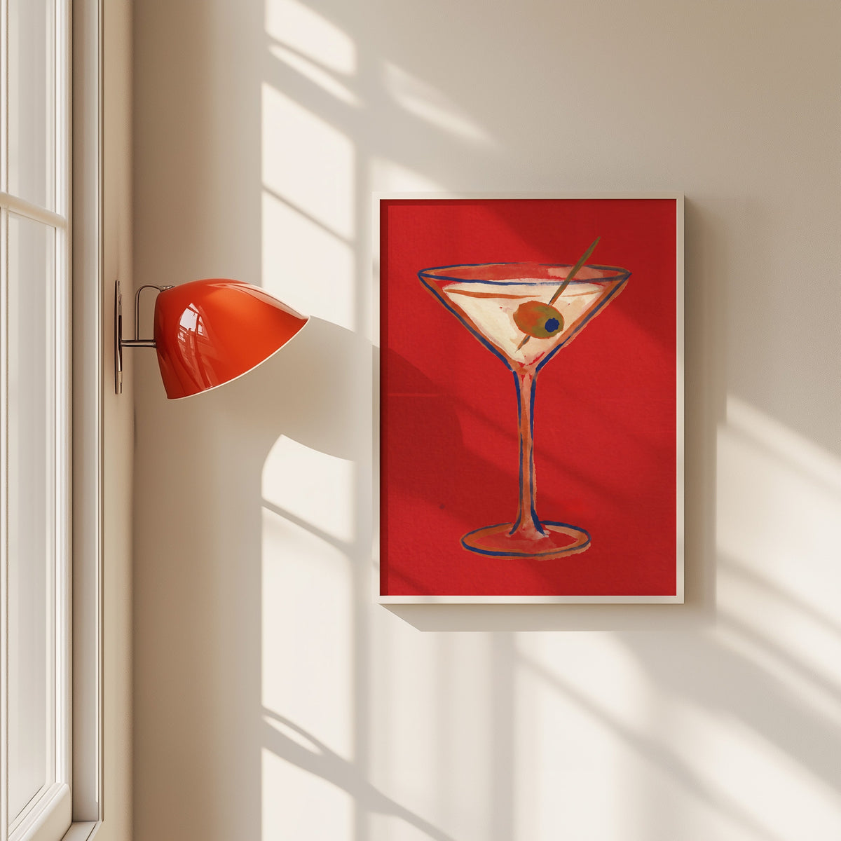 Martini with olive print in a white frame beside a red wall sconce