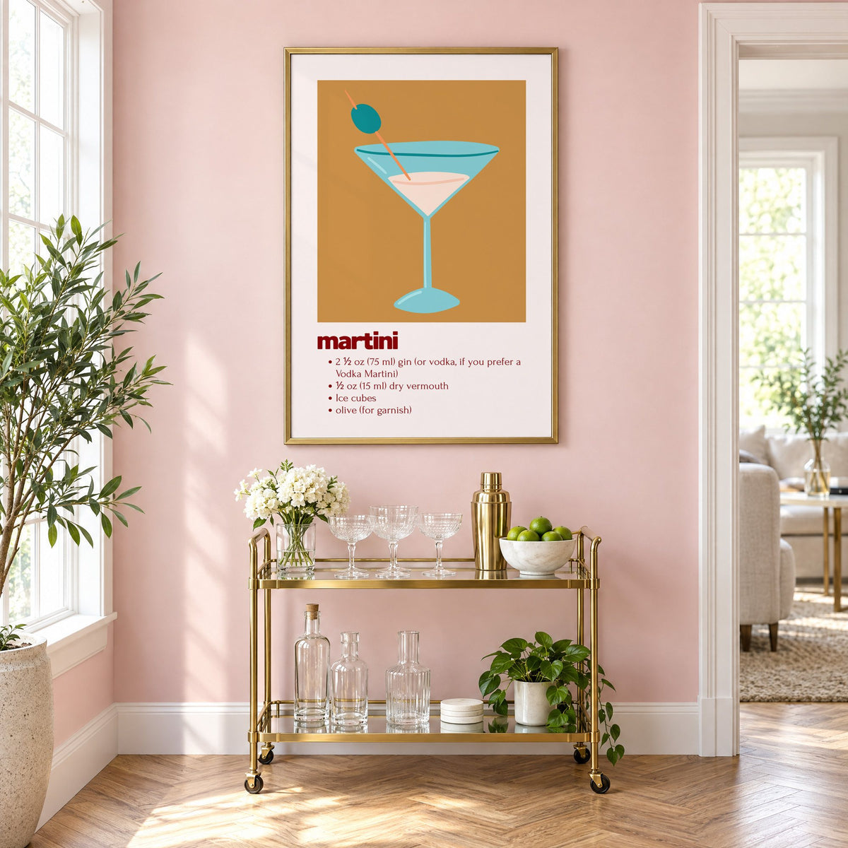 martini recipe olive glass ochre card print in a brass frame on a blush pink wall above a gold bar cart with glassware