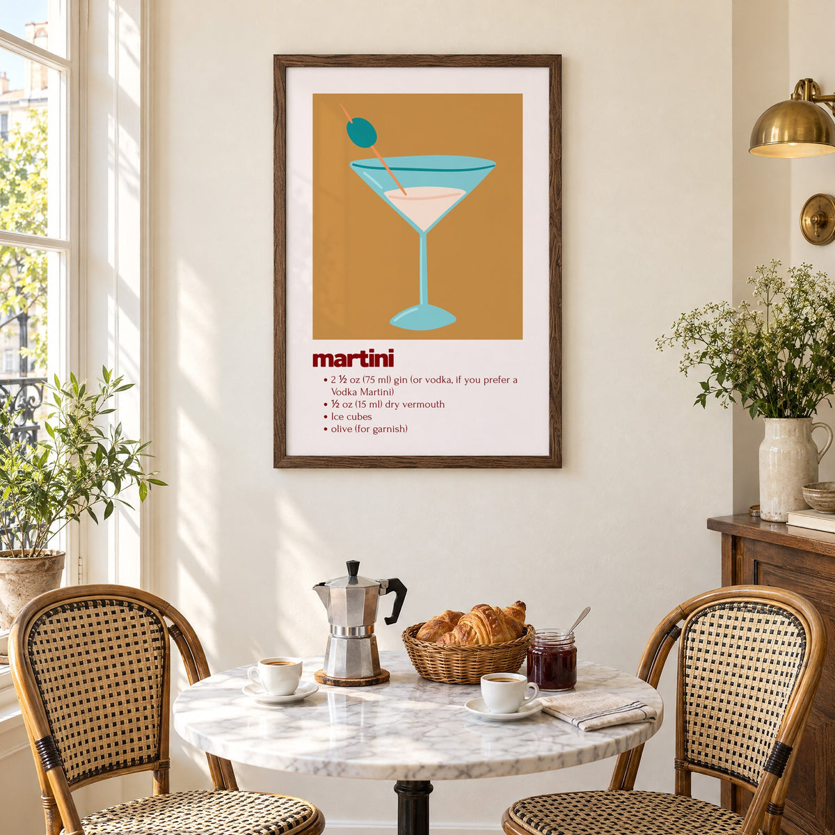 martini recipe olive glass ochre card print in a walnut frame above a marble bistro table with croissants and rattan chairs
