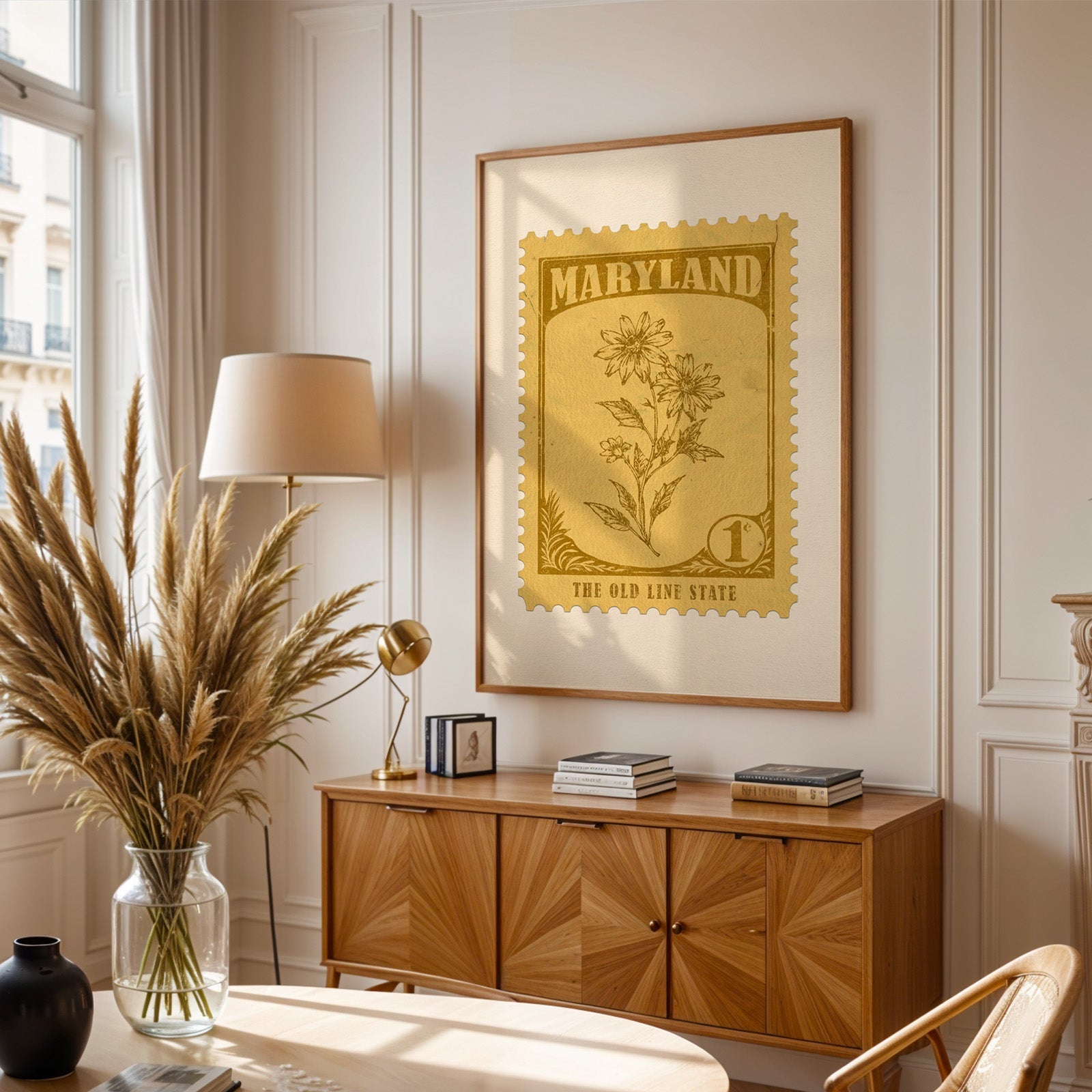 Maryland stamp print framed above a wooden sideboard, pampas grass in a glass vase and a floor lamp