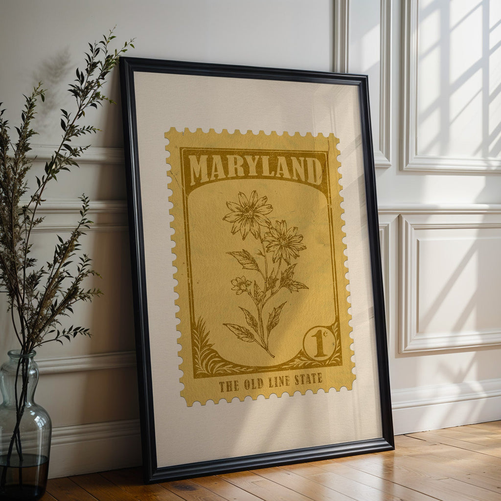 Maryland state flower print in a black frame leaning against a white panelled wall beside olive branches