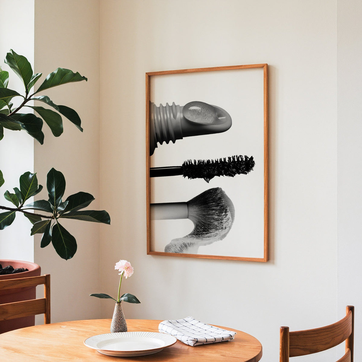 Macro gloss wand, mascara and blush brush print in a teak frame above a round wooden dining table