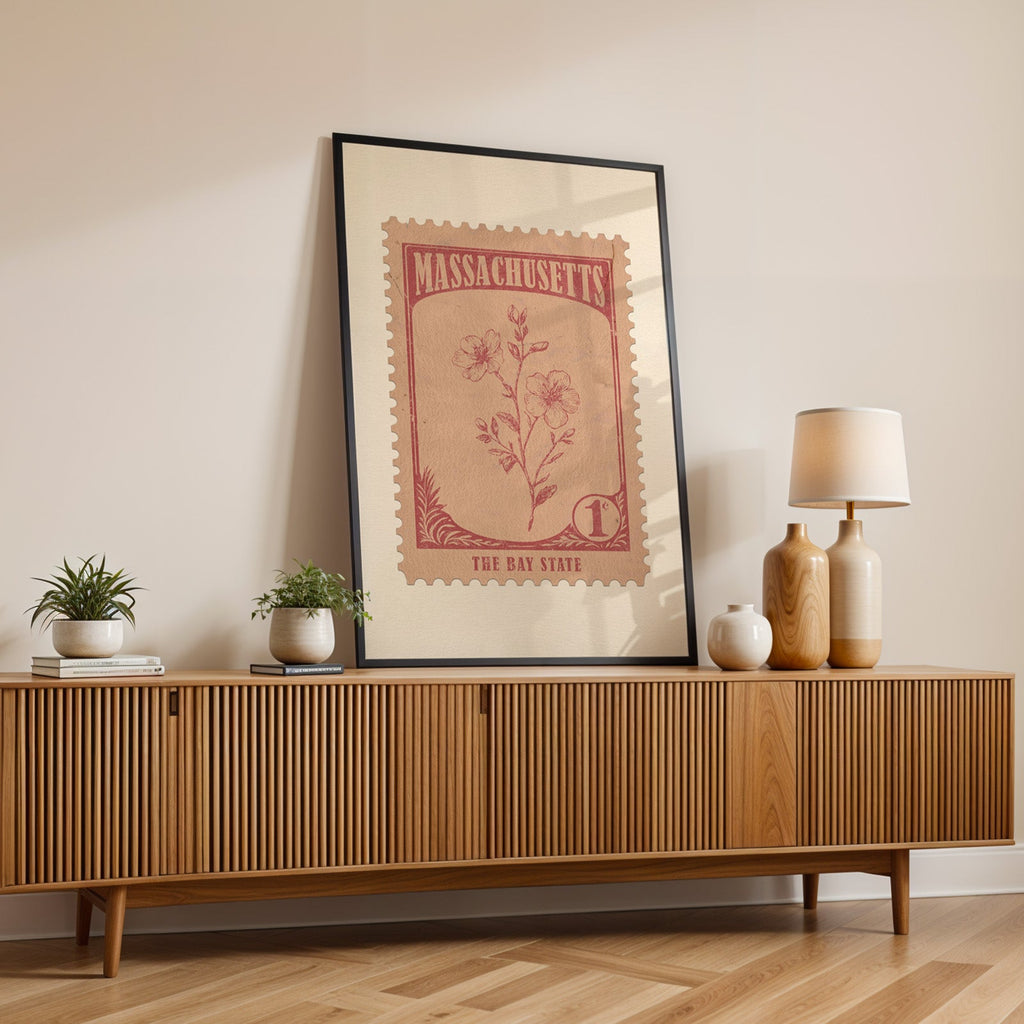 Massachusetts state flower print in a black frame leaning on a fluted wood credenza with vases and a lamp