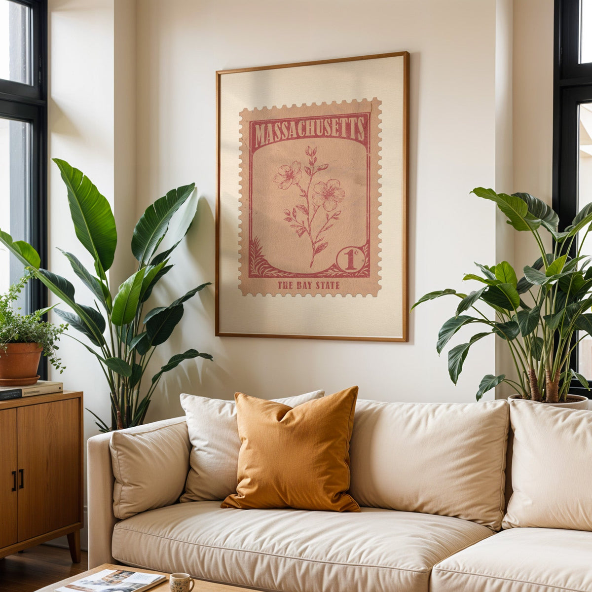 Massachusetts state flower print framed above a cream sofa with an ochre cushion and large plants either side