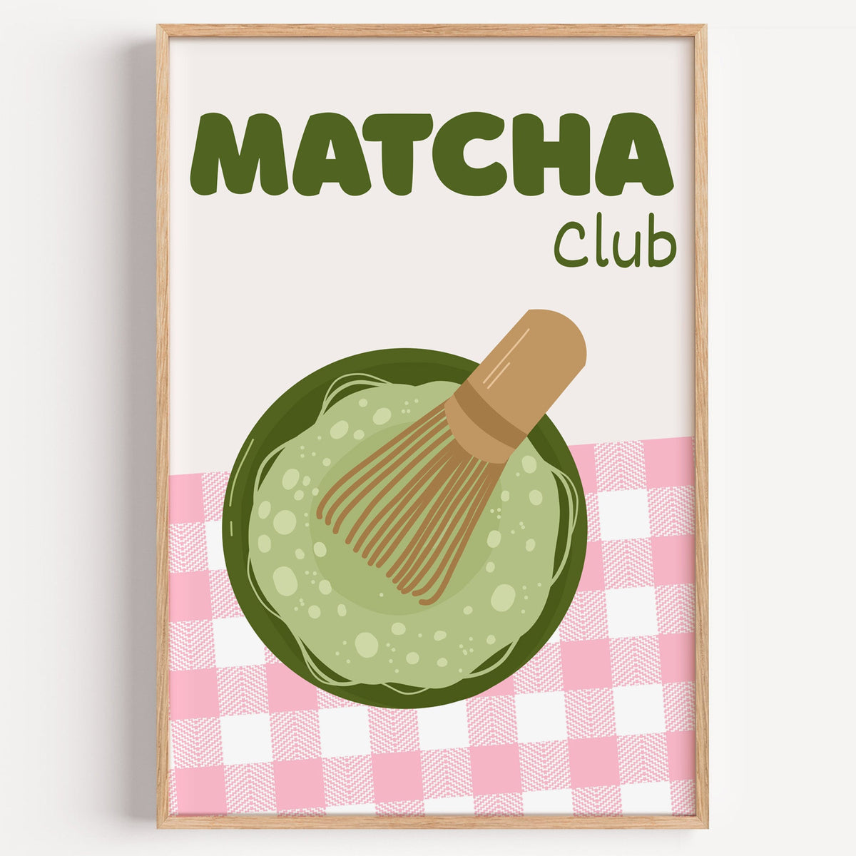 Matcha Club pink gingham print in a light oak frame on a plain white wall