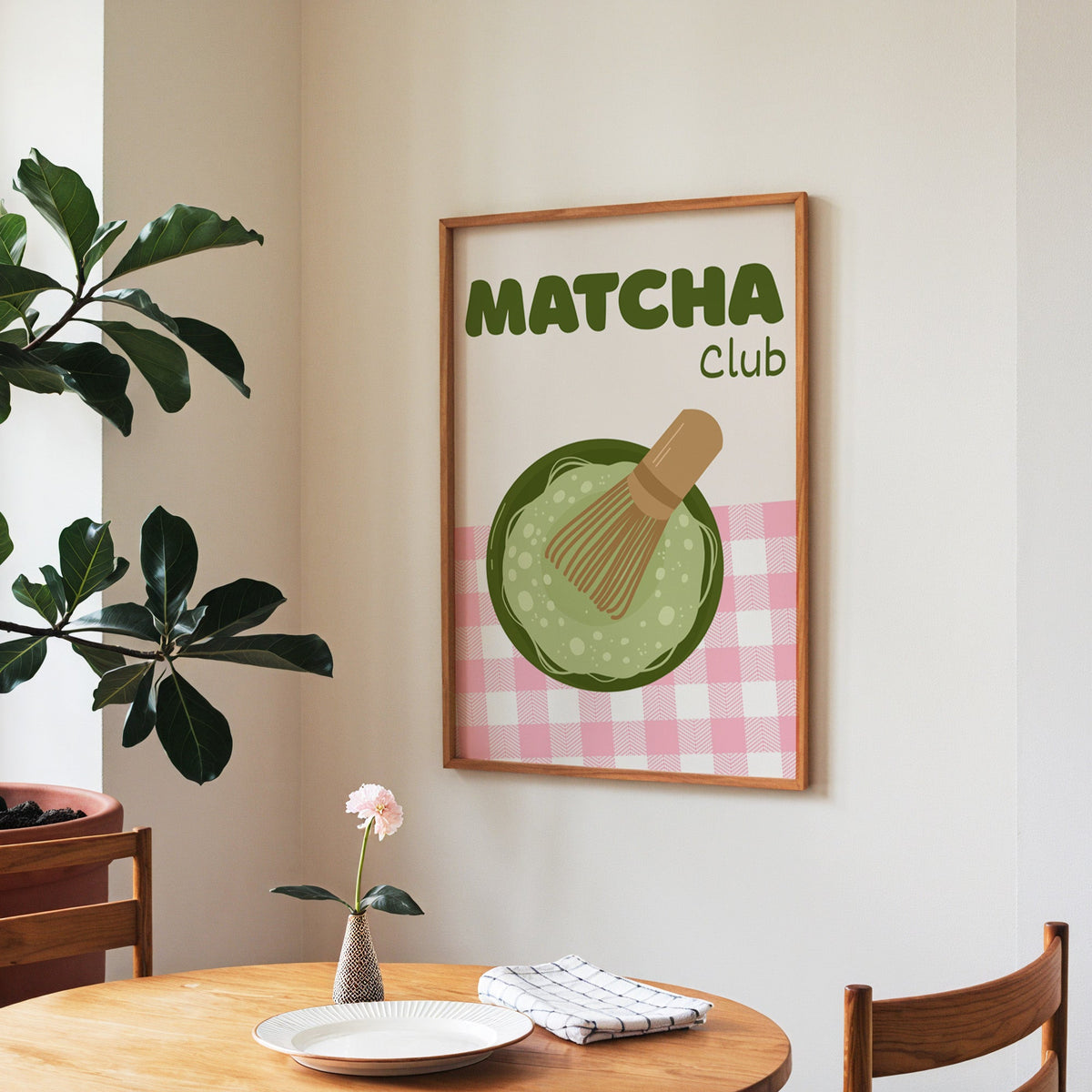 Matcha Club print in a walnut frame above a round table beside a fiddle-leaf fig