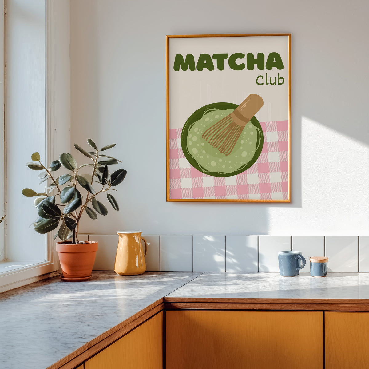 Matcha Club print shown in a gold frame above a marble counter in a tan kitchen