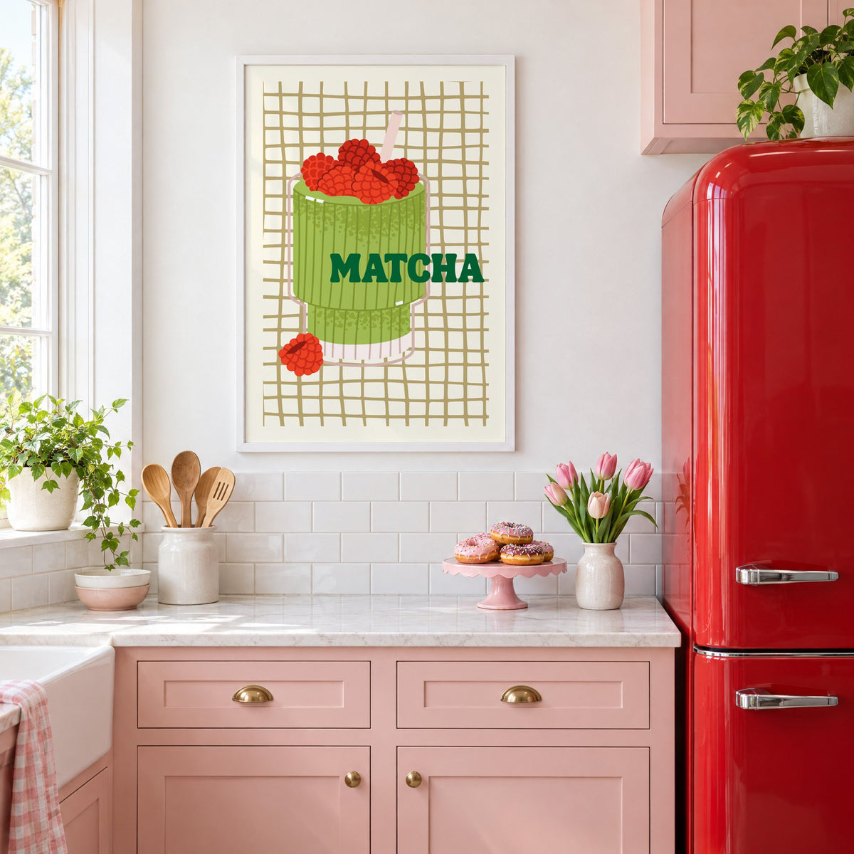 MATCHA raspberry glass on grid print in a white frame above pink cabinets beside a red retro fridge