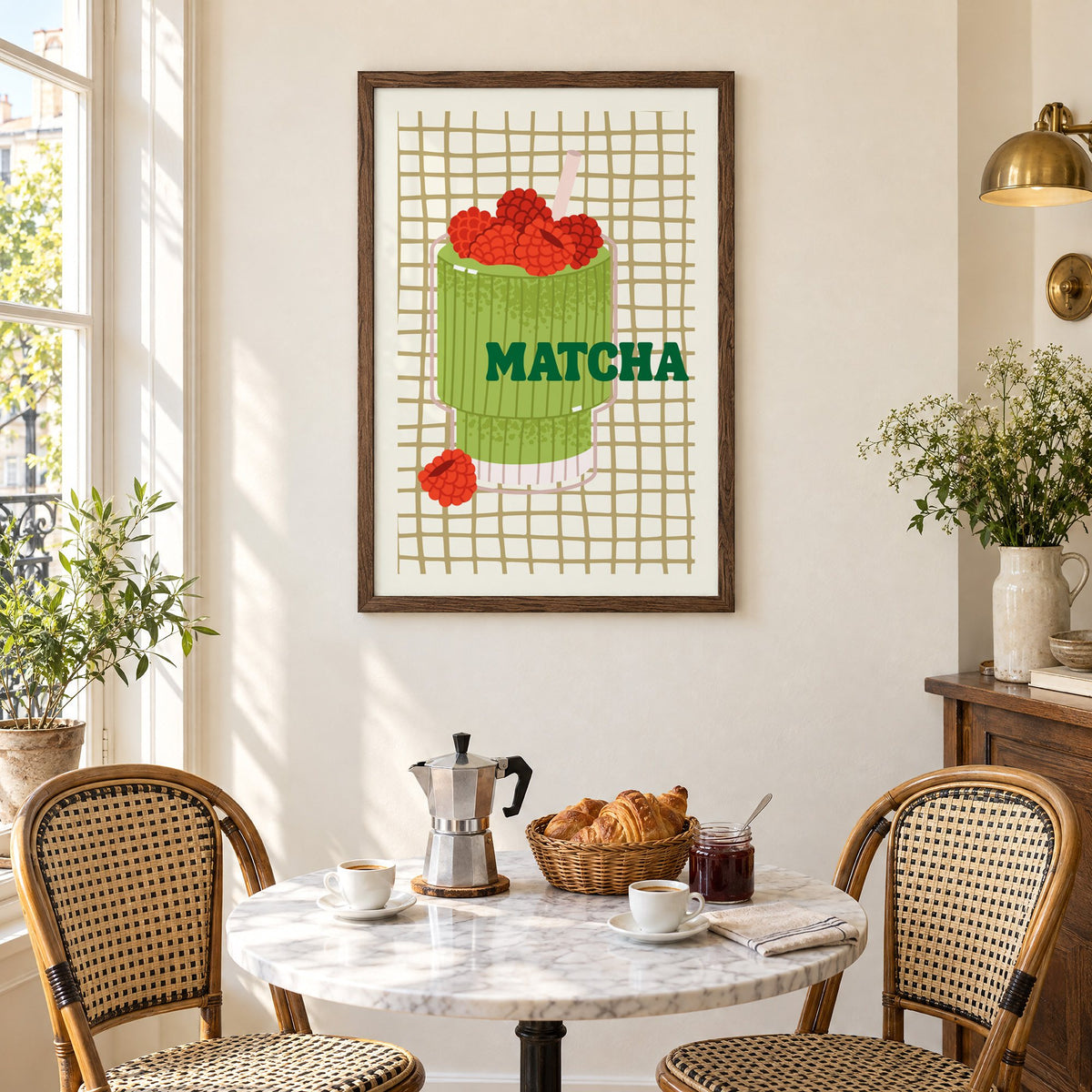 MATCHA raspberry glass on grid print in a walnut frame above a marble bistro table with croissants and rattan chairs