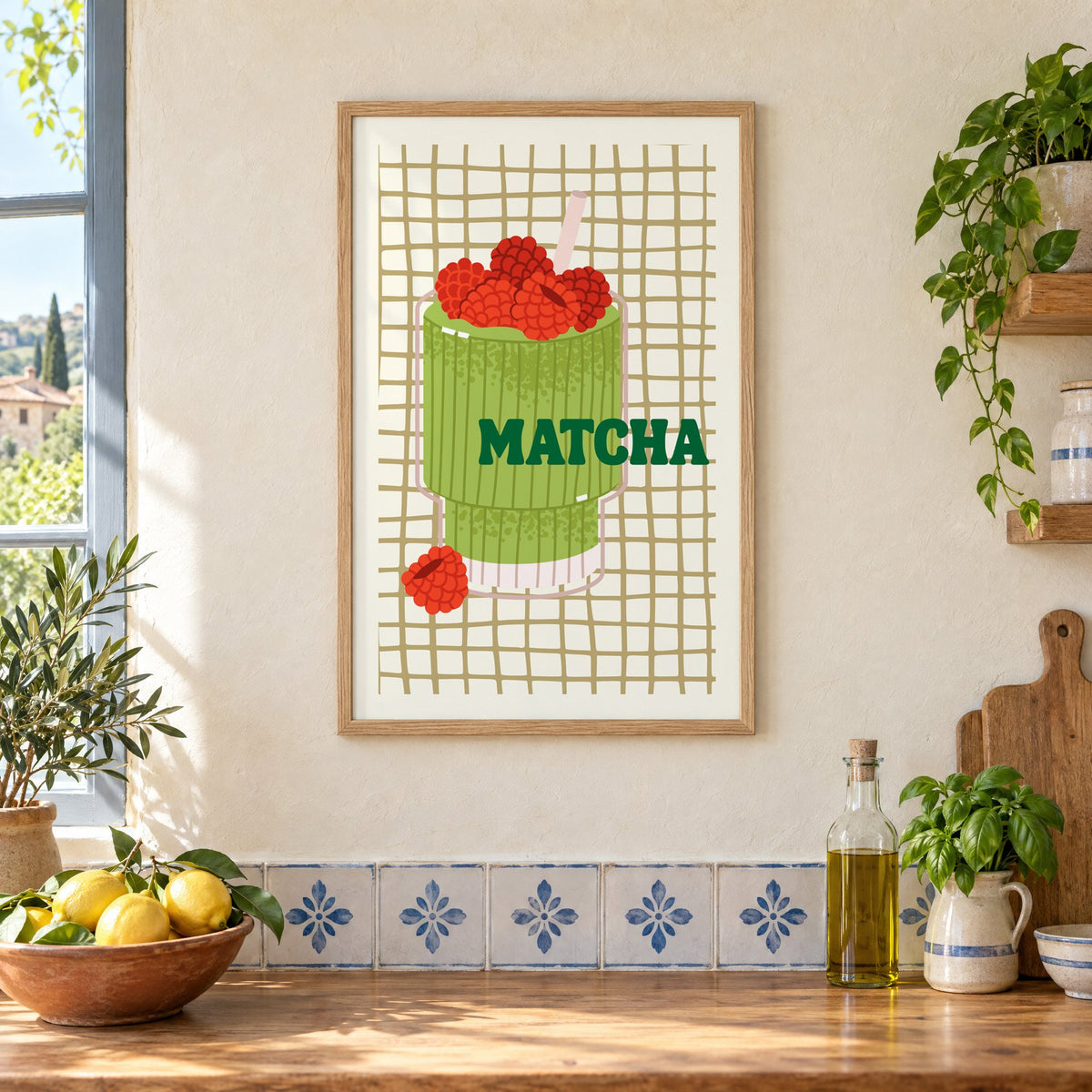 MATCHA raspberry glass on grid print in an oak frame on a cream plaster wall above a worktop with a bowl of lemons and blue-and-white tiles