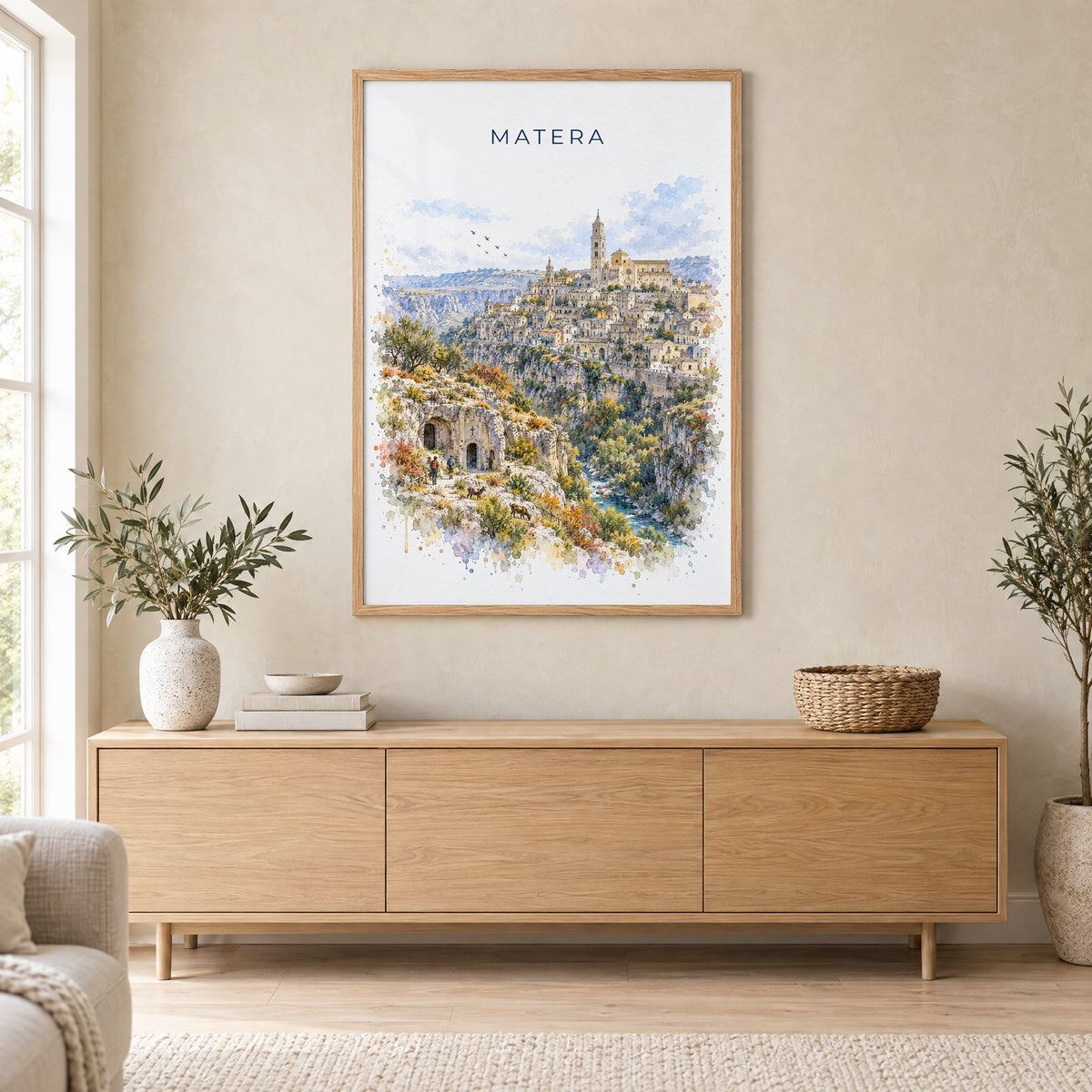 Matera watercolor print in an oak frame above a light wood sideboard in a Scandinavian living room