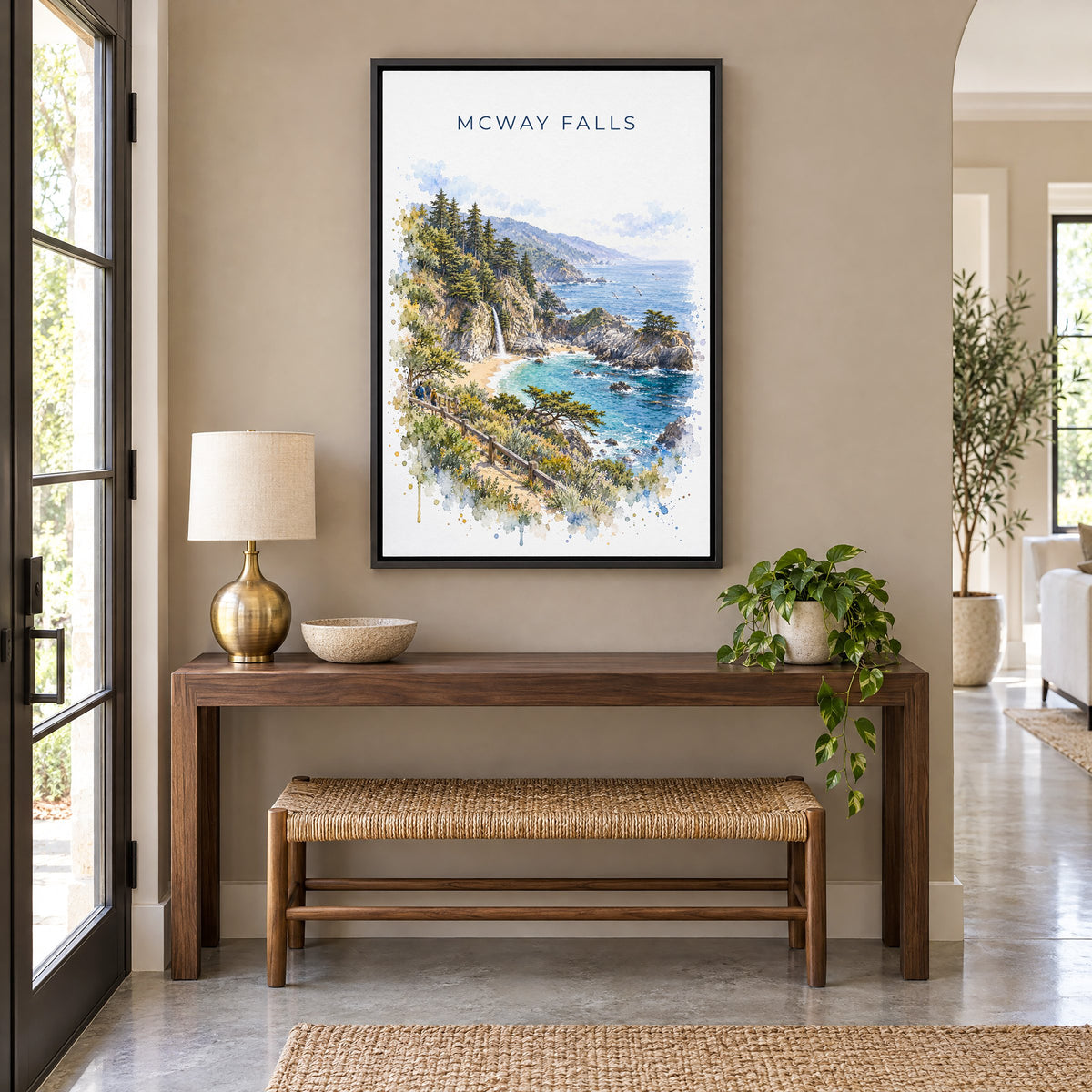 McWay Falls watercolor print as a black floater canvas above a walnut console and woven bench in an entryway