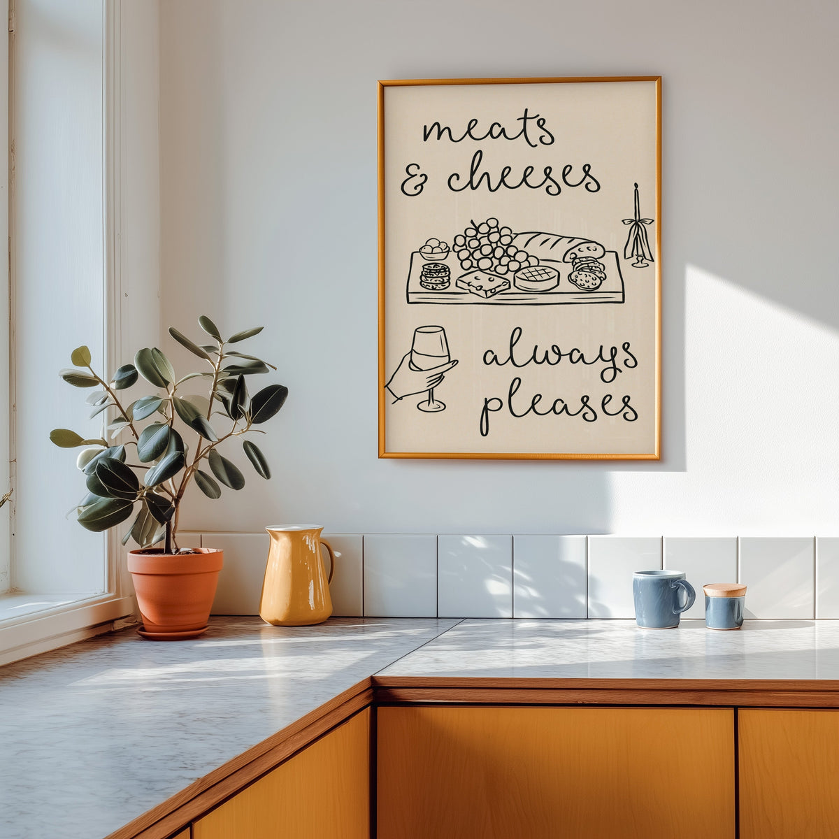 Charcuterie board print in a gold frame above a marble counter with a yellow jug