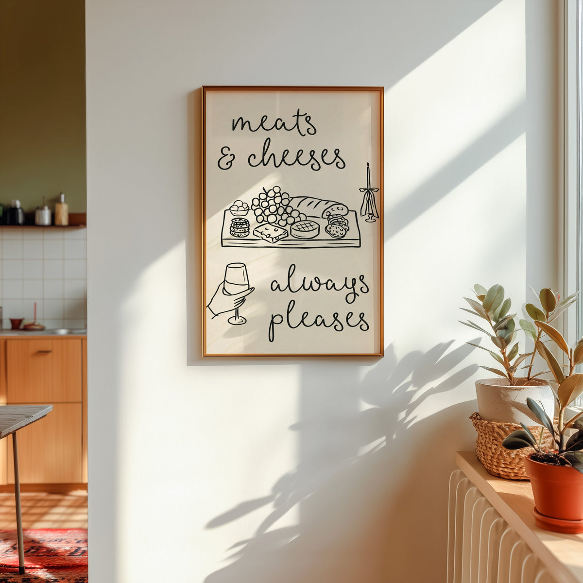Charcuterie board print in a gold frame in sunlight with plants and a kitchen beyond