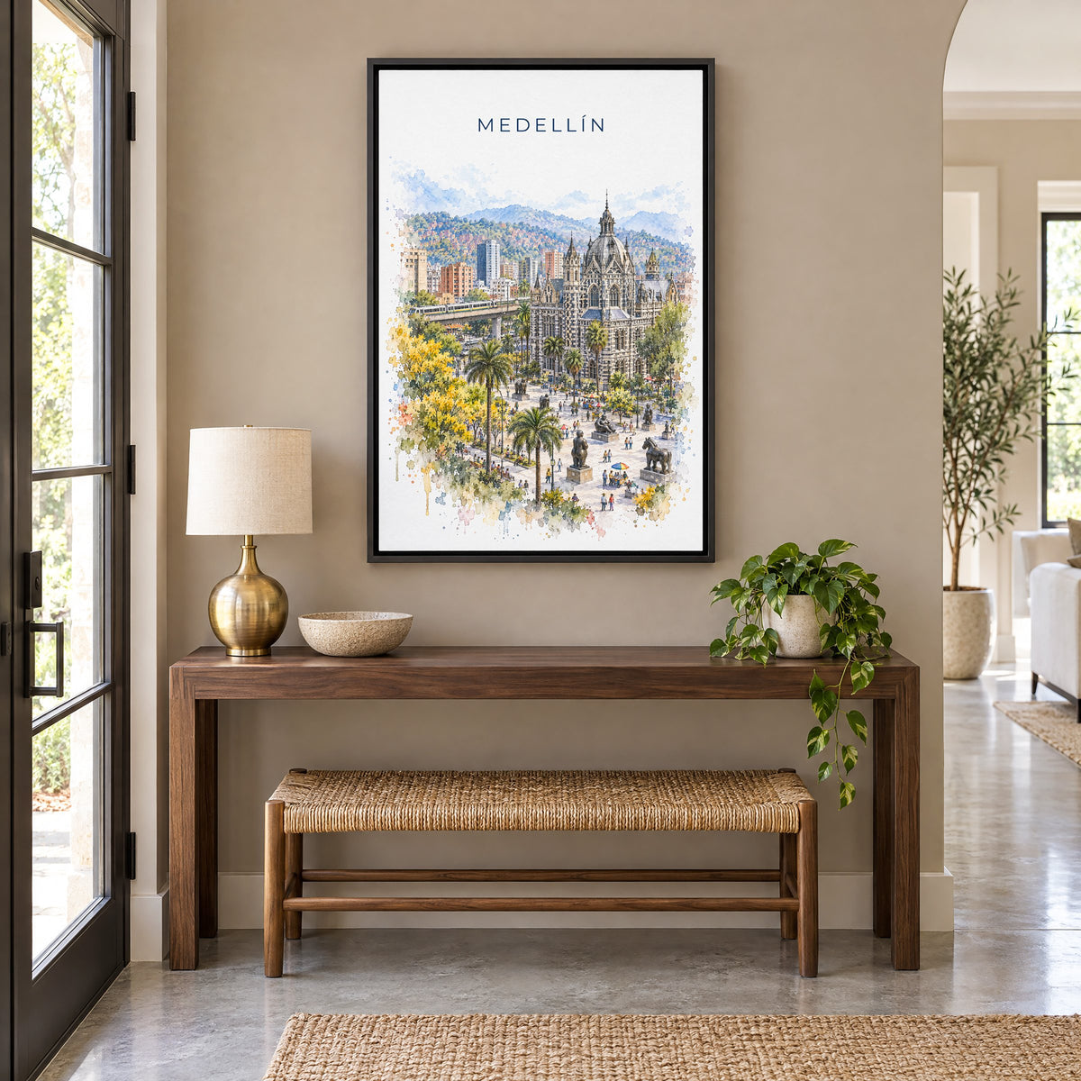 Medellín watercolor print as a black floater canvas above a walnut console and woven bench in an entryway