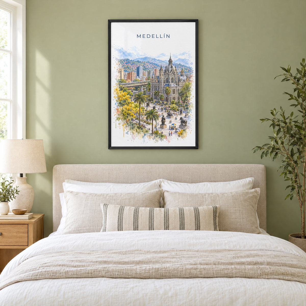 Medellín watercolor print in a black frame above an upholstered headboard in a sage green bedroom